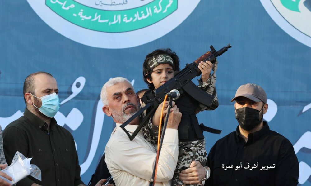 Yahya Sinwar holding a boy with a gun in his hand